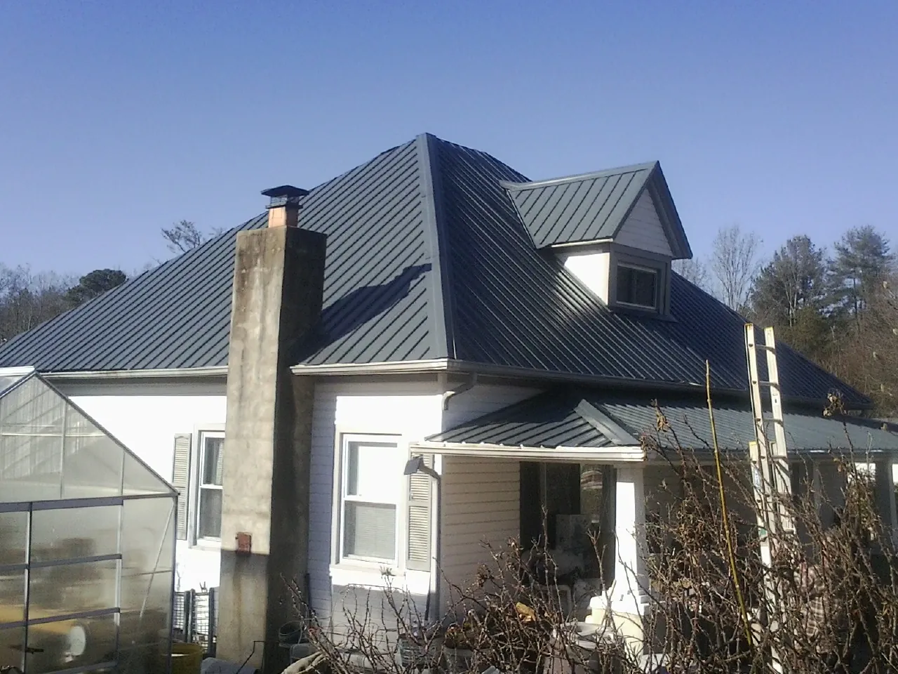 Dark blue standing seam metal roof on a white farmhouse with dormer — Slate & Tile Roof Repair by Roofing Brothers in Russia