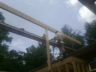 Carpenter setting a ridge beam over a new addition frame — Ice Dam Removal by Roofing Brothers in Russia