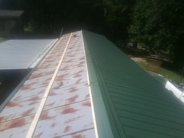Old rusted panels beside newly installed green metal roofing — Wind Damage Roof Repair by Roofing Brothers in Russia