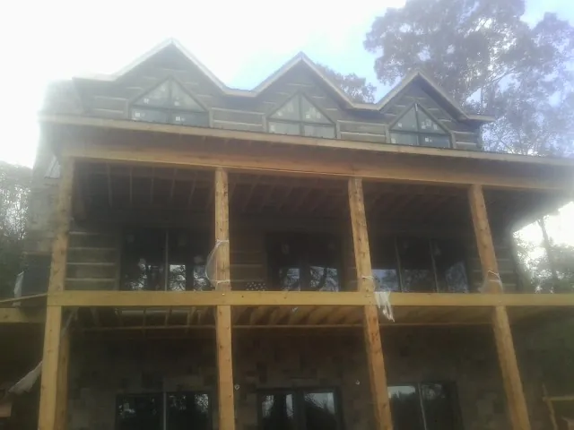 Dormers and porch framing on a large log home under construction — Roof Coating work by our crew in Russia