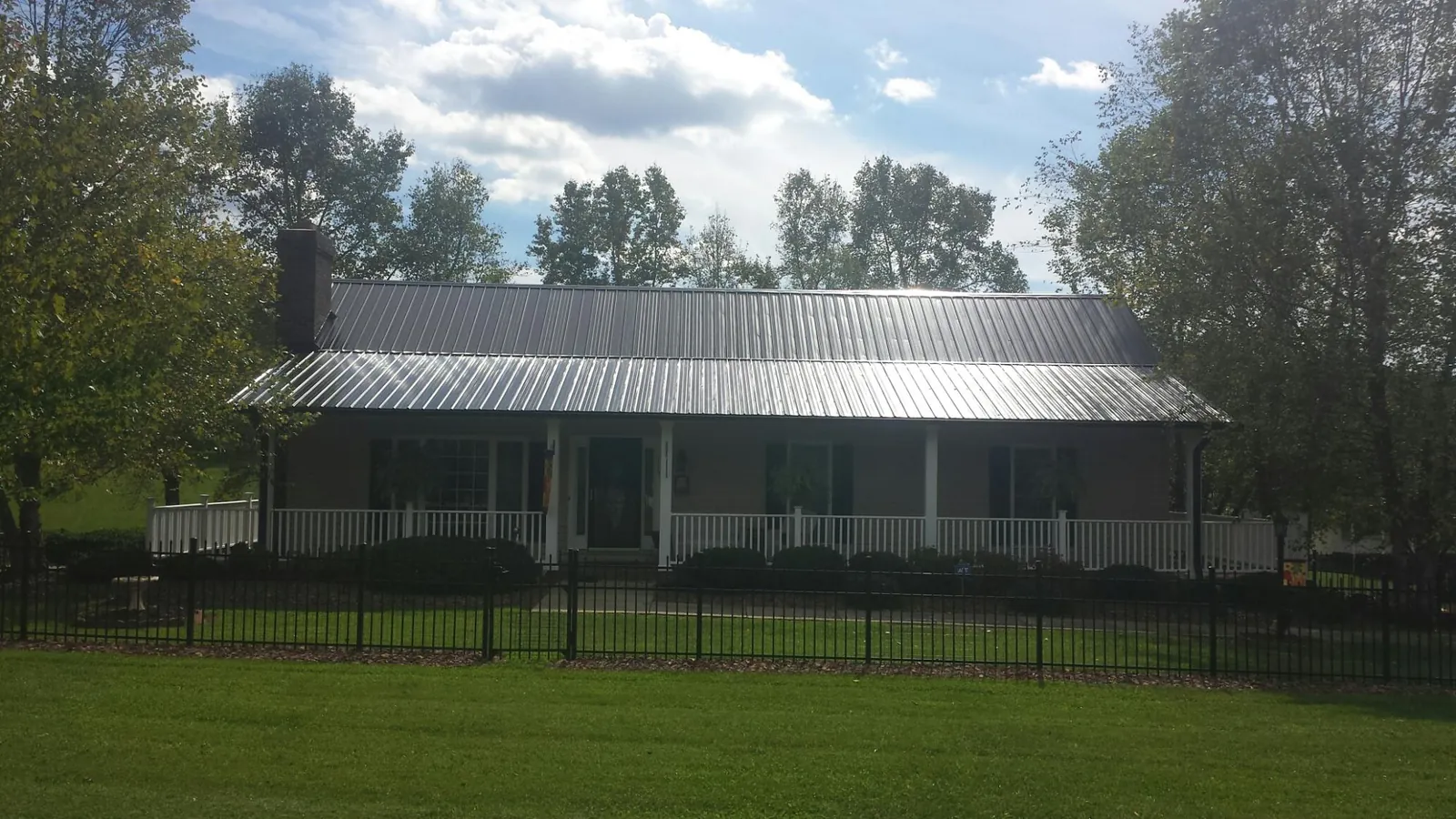Gray metal roof on a brick ranch with a full width front porch — Gutter Guard Installation work by our crew in Russia