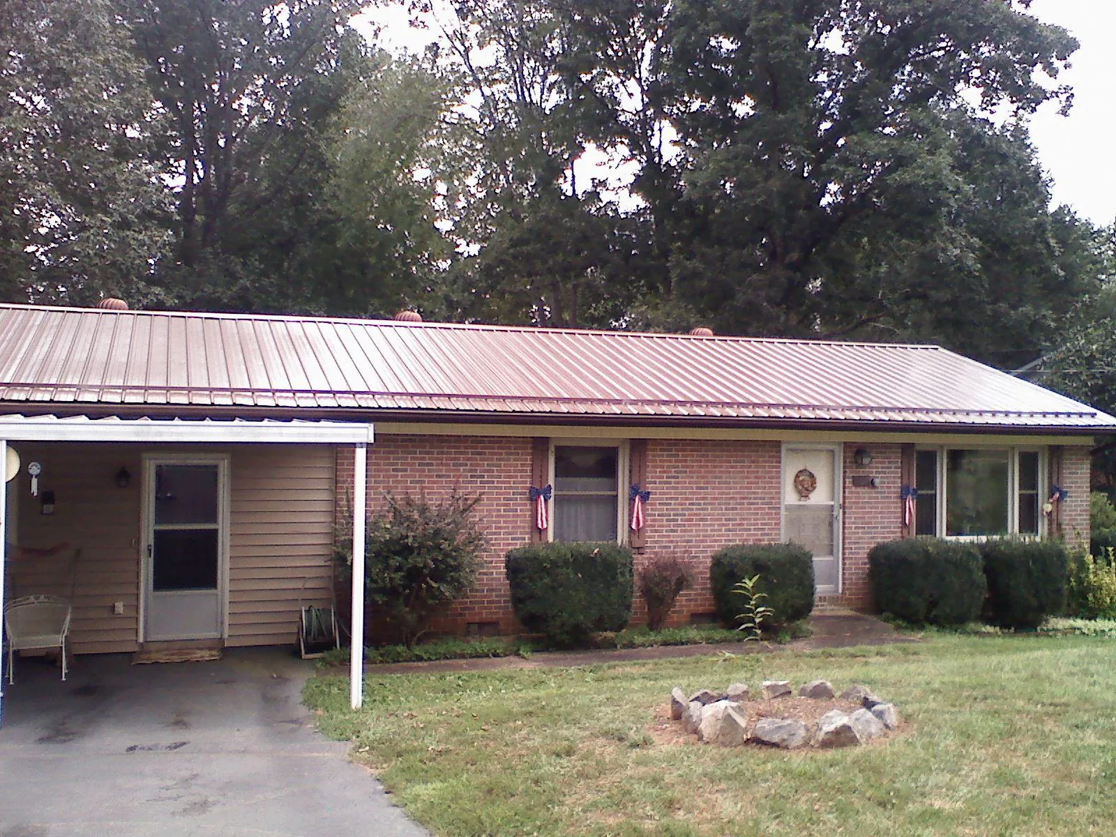 Bronze metal roof and carport on a brick ranch home — Roof Repair work by our crew in Russia