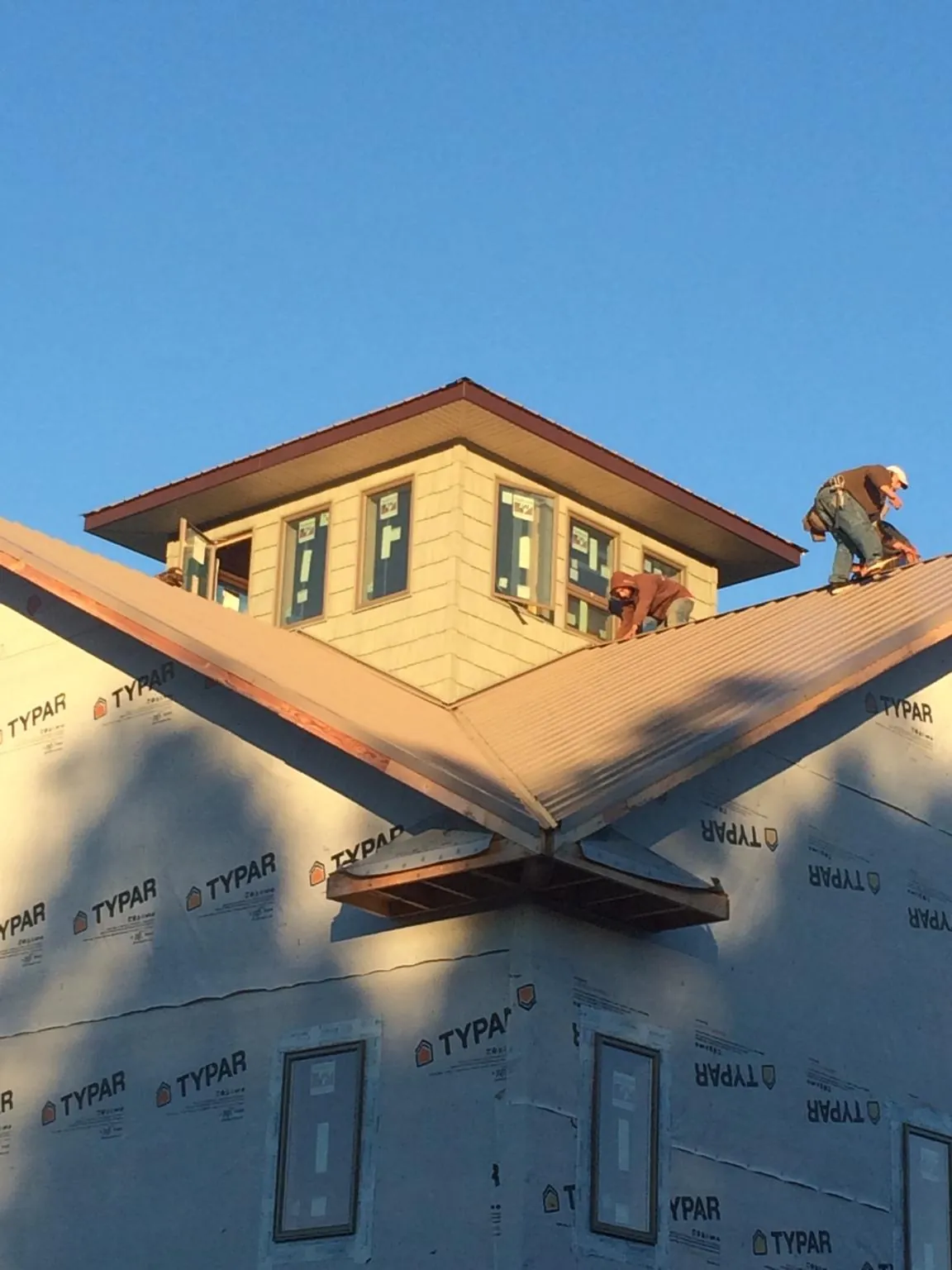 Roofers working around a rooftop cupola on a new metal roof at sunset — Roof Waterproofing in Russia by Roofing Brothers